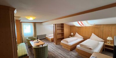 Bright room with wooden furniture, two beds, sitting area and window