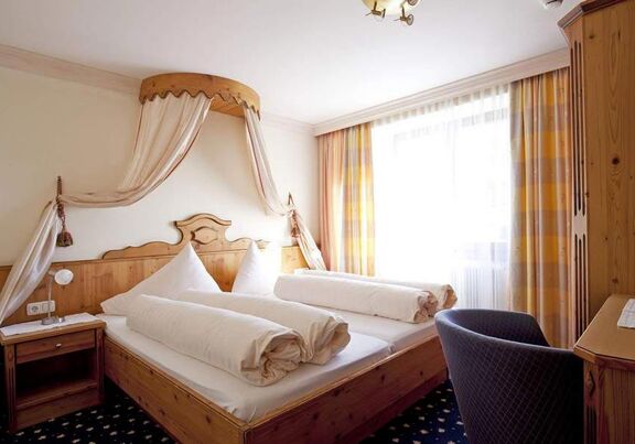 Helles Schlafzimmer mit Himmelbett, Holzdetails und gemütlicher Atmosphäre.