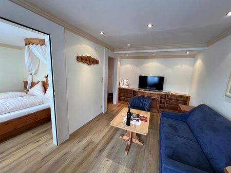 Elegantes Wohnzimmer mit blauer Couch, Holzdetails und angrenzendem Schlafzimmer.