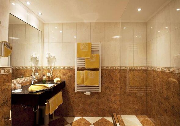 Luxuriöses Badezimmer mit glänzenden Fliesen und weichen Handtüchern in warmem Licht.