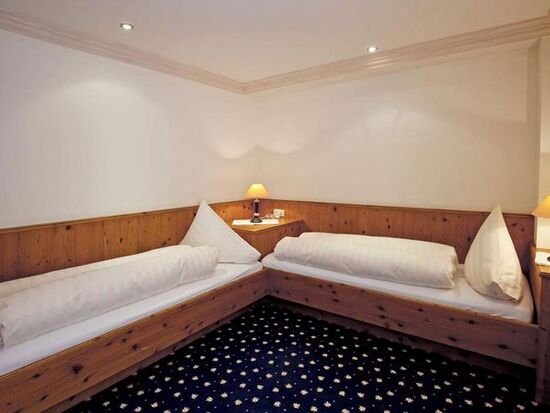 Zwei Einzelbetten mit Holzverkleidung und weichen Kissen in einem behaglichen Raum.