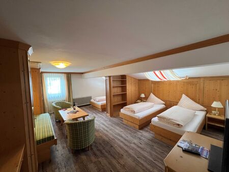 Helles Zimmer mit Holzmöbeln, zwei Betten, Sitzecke und Fenster