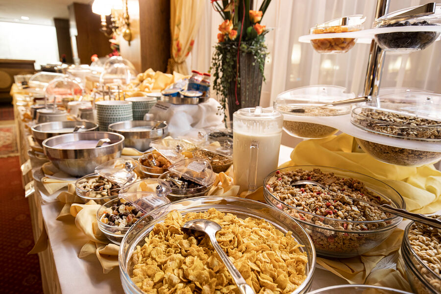 Vielfältiges Frühstücksbuffet mit Cerealien, Nüssen, Gebäck und frischer Milch.