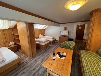 Zimmer mit Holzmöbeln, Fernseher, gemütlichen Betten und Sitzbereich für entspannte Aufenthalte.