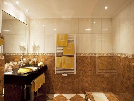 Luxuriöses Badezimmer mit glänzenden Fliesen und weichen Handtüchern in warmem Licht.