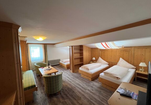 Helles Zimmer mit Holzmöbeln, zwei Betten, Sitzecke und Fenster