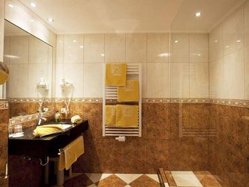 Luxuriöses Badezimmer mit glänzenden Fliesen und weichen Handtüchern in warmem Licht.