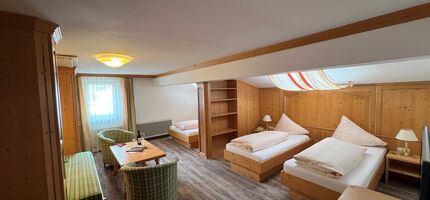 Bright room with wooden furniture, two beds, sitting area and window