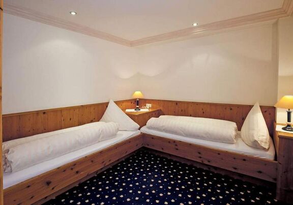 Zwei Einzelbetten mit Holzverkleidung und weichen Kissen in einem behaglichen Raum.