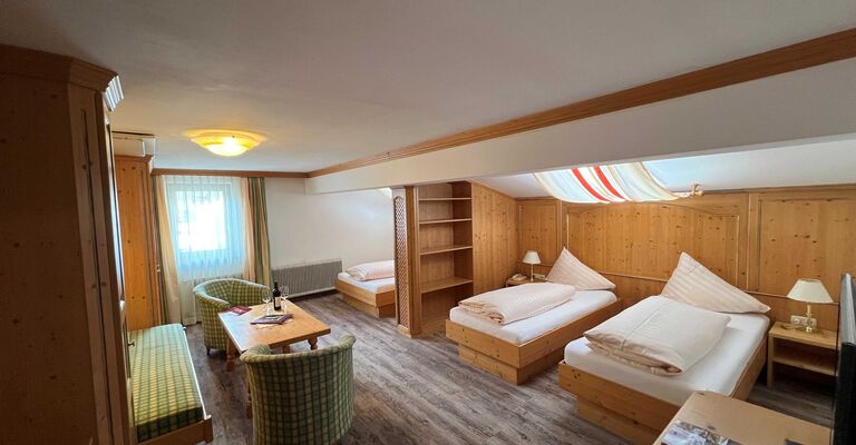 Bright room with wooden furniture, two beds, sitting area and window