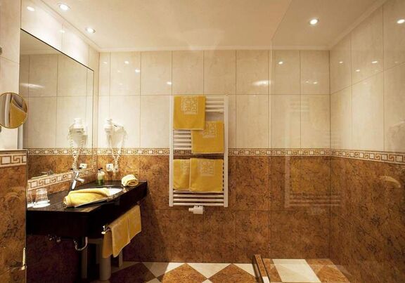 Luxuriöses Badezimmer mit glänzenden Fliesen und weichen Handtüchern in warmem Licht.