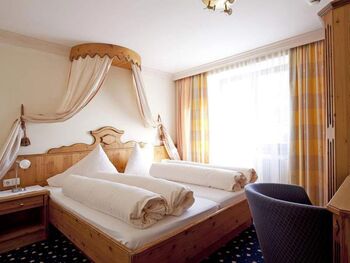 Helles Schlafzimmer mit Himmelbett, Holzdetails und gemütlicher Atmosphäre.