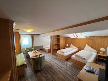 Helles Zimmer mit Holzmöbeln, zwei Betten, Sitzecke und Fenster