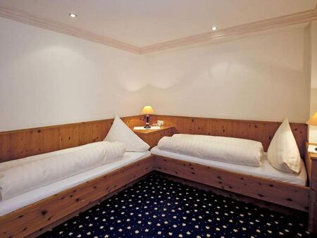 Zwei Einzelbetten mit Holzverkleidung und weichen Kissen in einem behaglichen Raum.